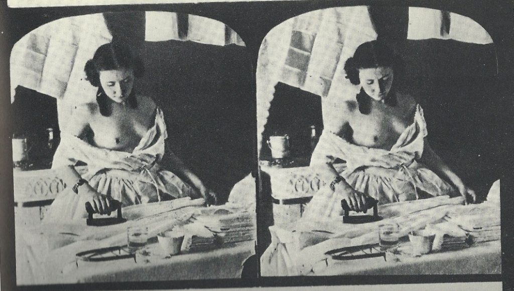 Stereograph image of a woman ironing clothes. The woman is wearing a loose-fitting dress and her breast is partially exposed