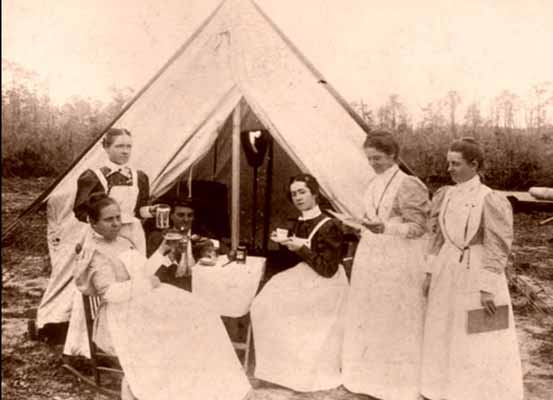 Six nurses and doctors having a drink under a medical tent on the field.