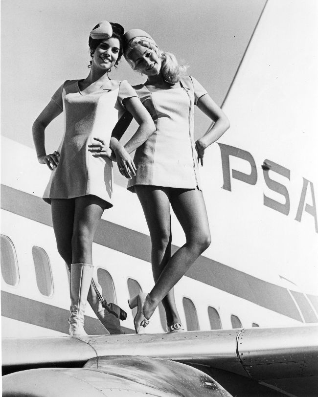 Two female stewardesses pose on an airplane wing for an early 1970s Pacific Southwest Airlines publicity shoot.