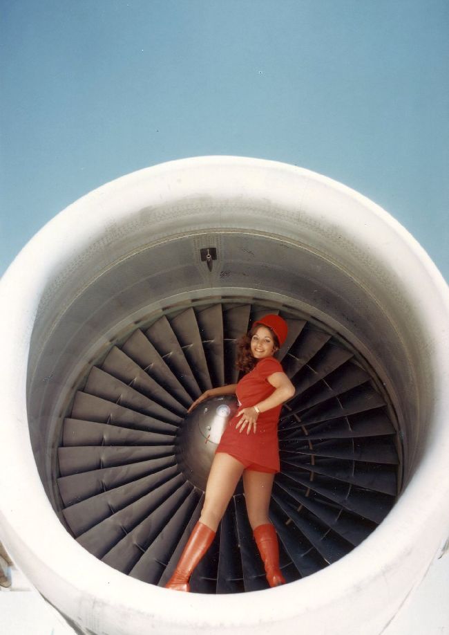A Pacific Southwest Airlines flight attendant poses in an engine to show off her skimpy, bright red uniform.
