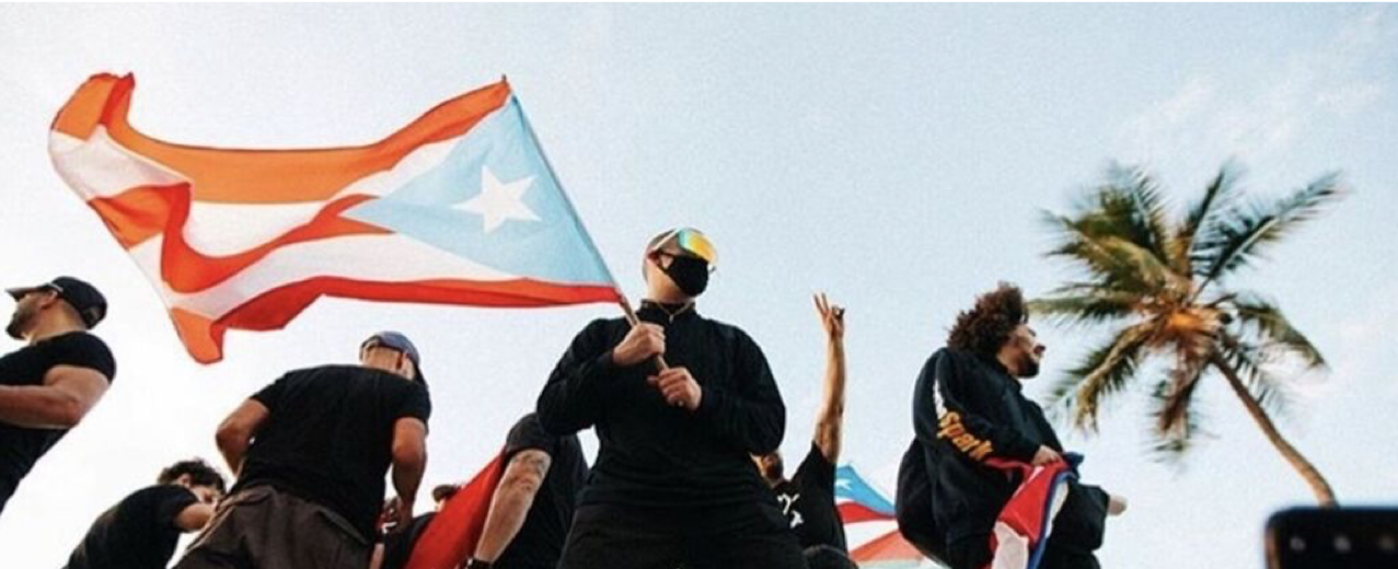 Alt Text: Man holding a Puerto Rican flag.