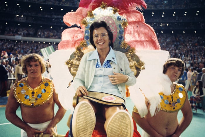 Billie Jean King entering the Battle of the Sexes Match carried by men on a throne that is extravagant and vibrantly colored.