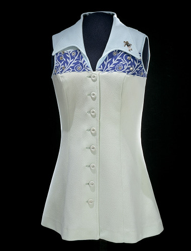 Image of Billie Jean King’s Tennis Dress from the Battle of the Sexes in 1973 that is vibrant light blue and light green with a high neck collar. Dress is standing alone in the Smithsonian.